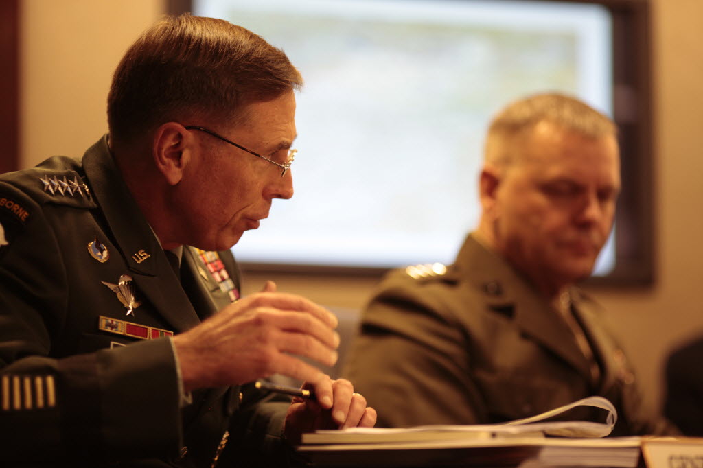Gen. David Petraeus, in uniform, gestures over an open binder, with Gen. James Cartwright beside him, during a Situation Room meeting.