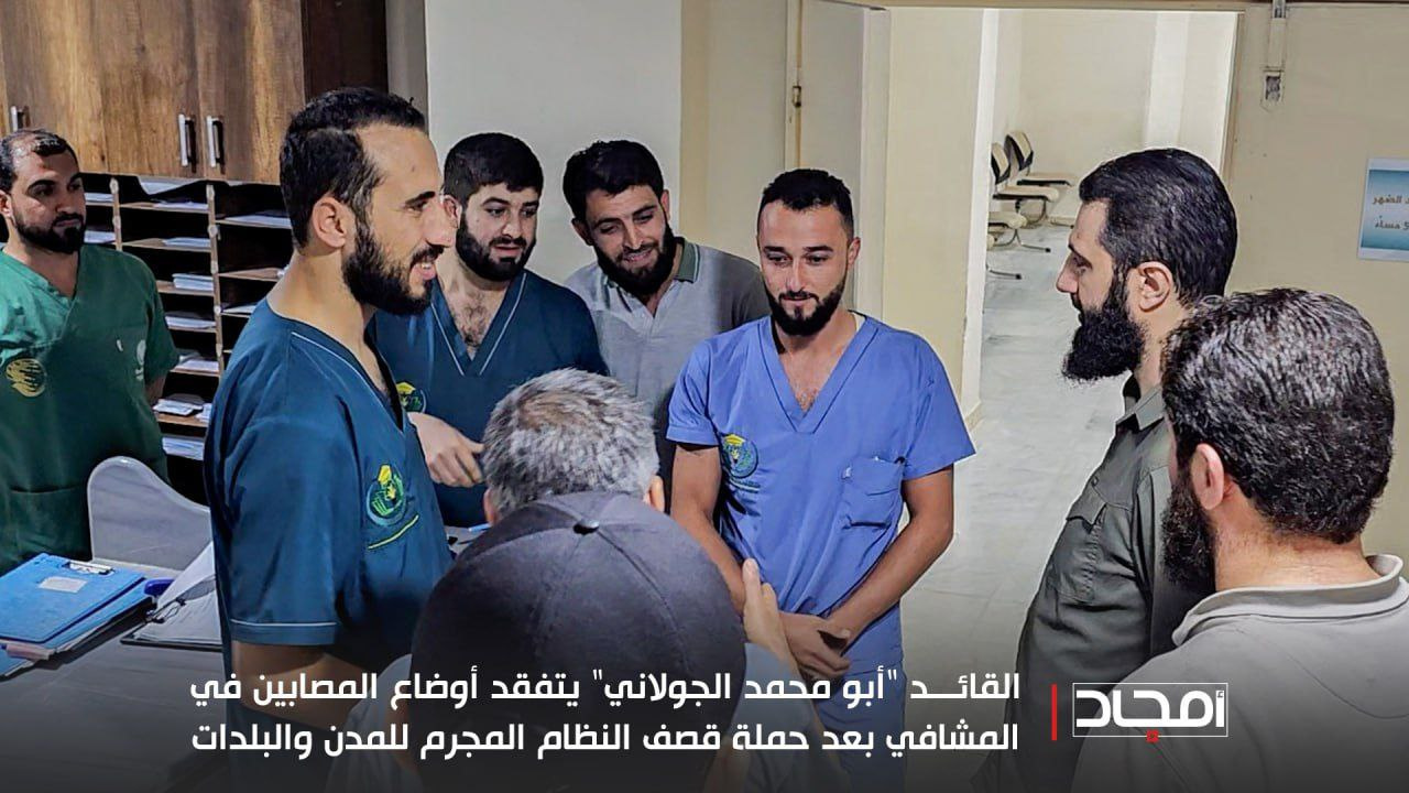 Al-Julani standing with hospital staff in blue scrubs in a ward, October 9, 2023.