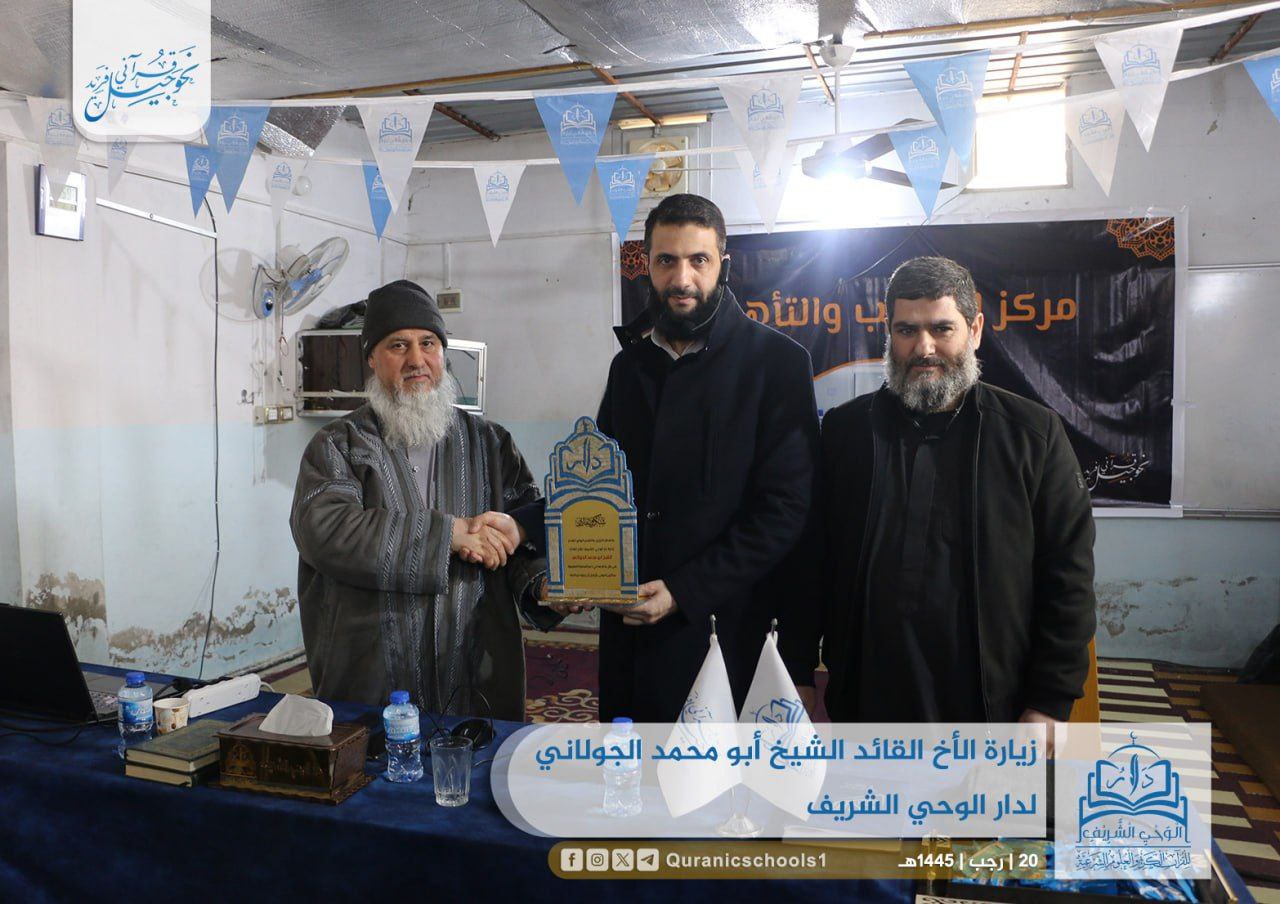 Al-Julani receiving a plaque from a sheikh at the Dar al-Wahi al-Sharif Quranic school, with the school’s logo in the corner, February 1, 2024.